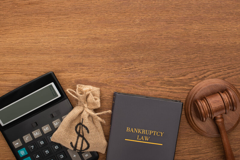 Bankruptcy law book with money bag, gavel, and calculator