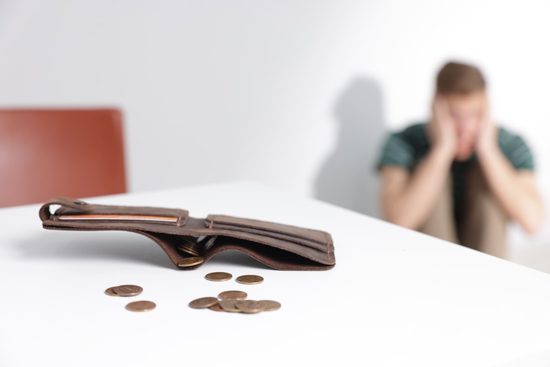 upset man sitting behind empty wallet