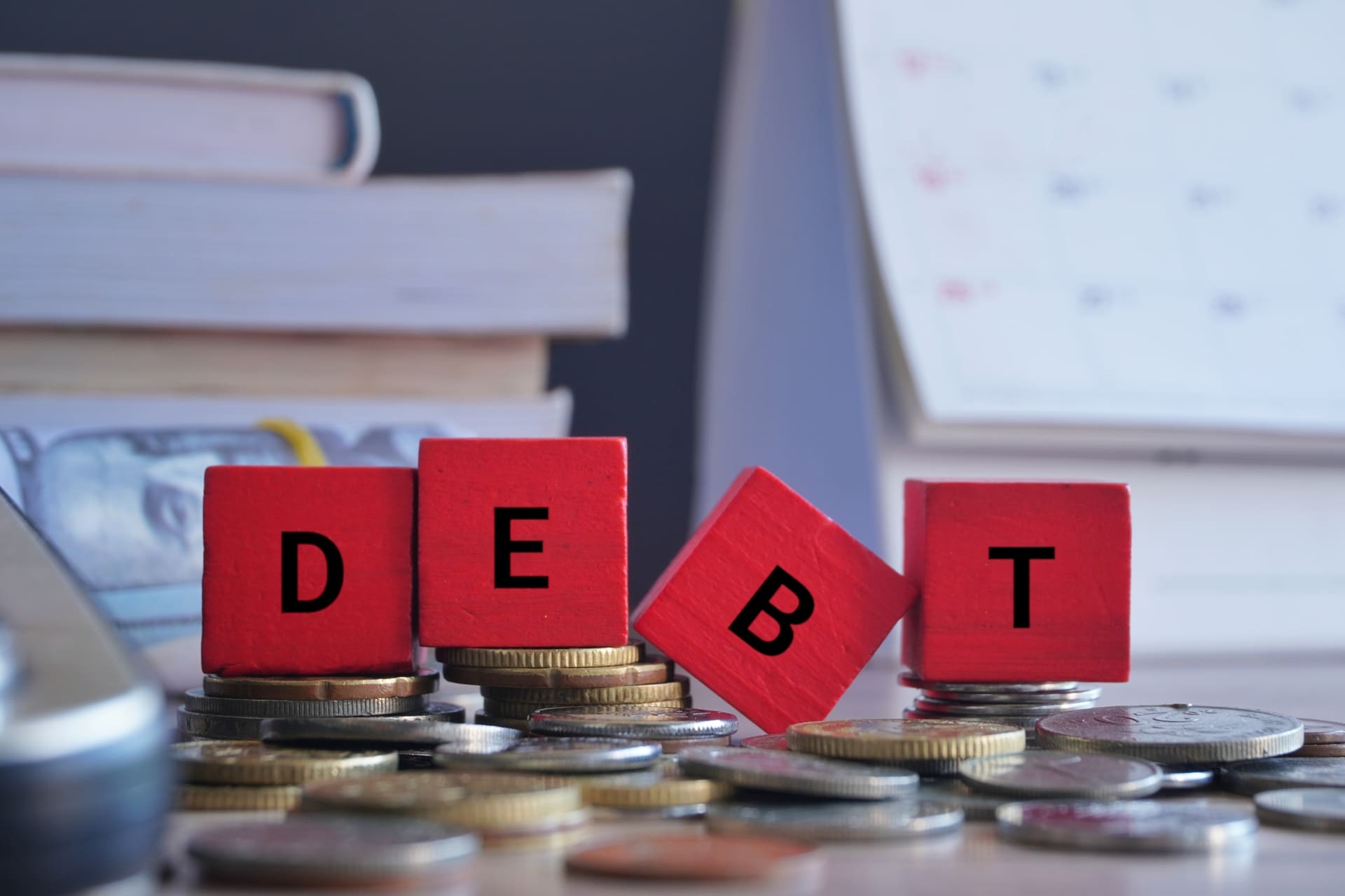 wooden cubes with word debt surrounded by money