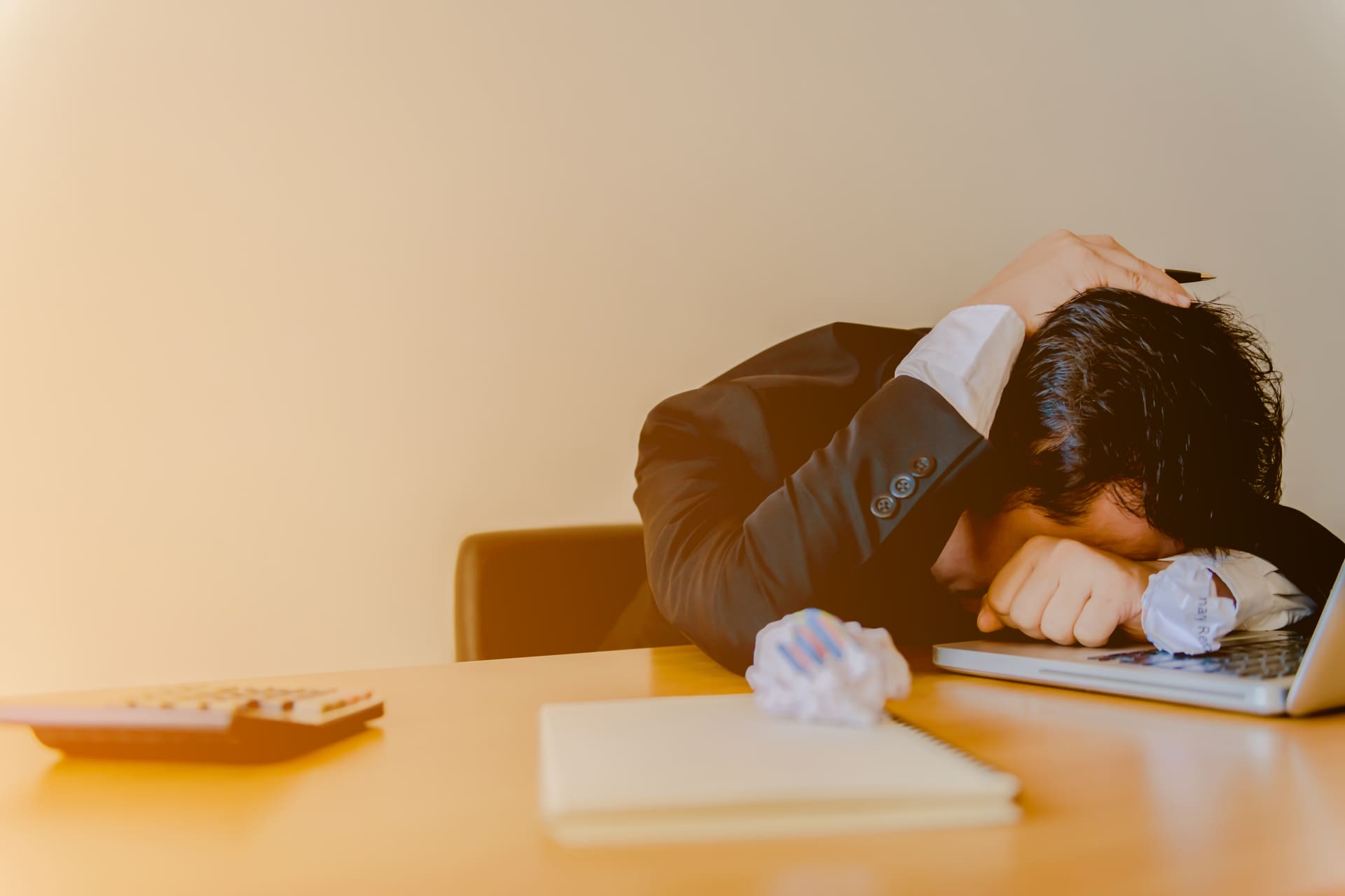 businessman burying head in arms due to stress