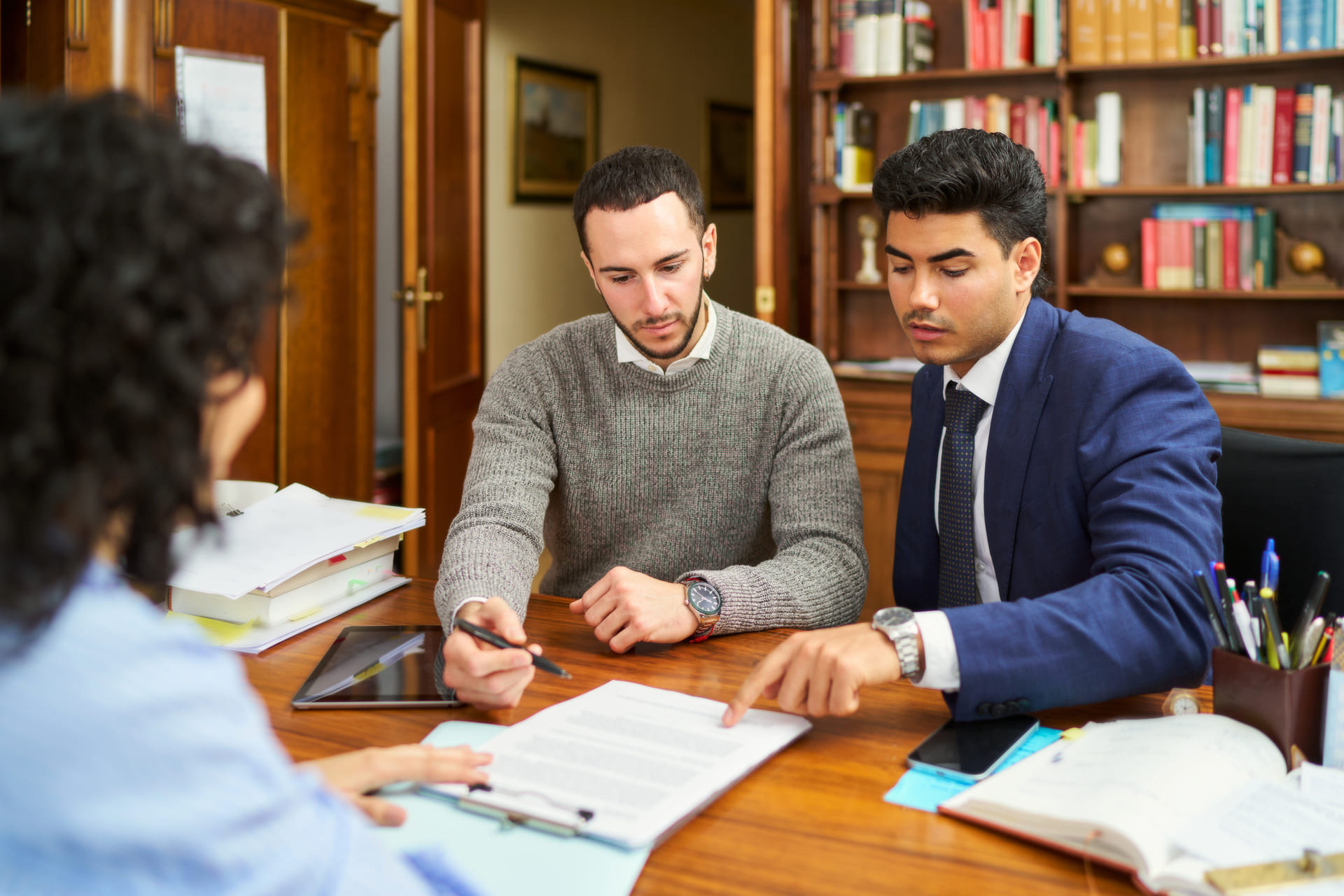 three-men-are-sitting-at-a-table-with-papers and lawyer