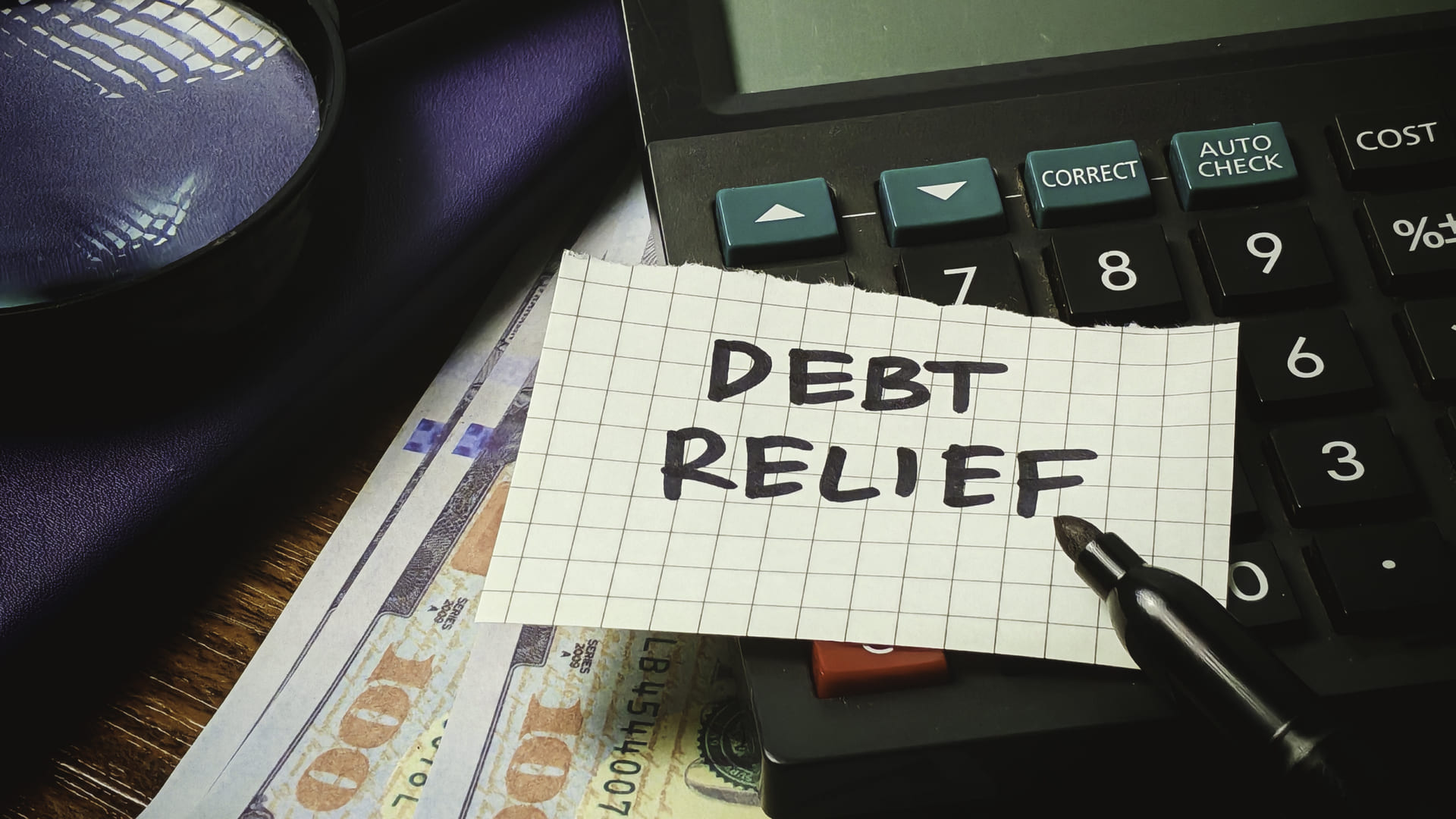 a pen and paper with "Debt relief" written on it