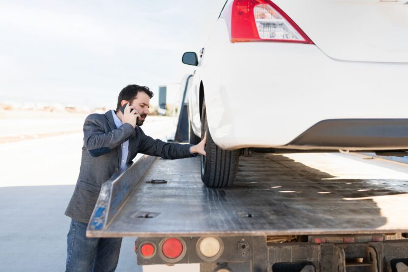 man-on-phone-with-car-on-tow-truck