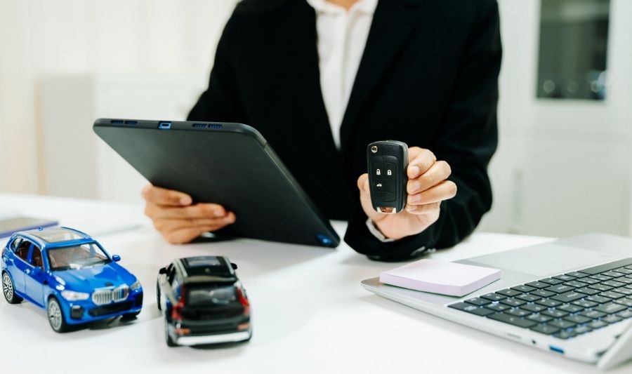 businesswoman holding a car remote key and tablet with important documents