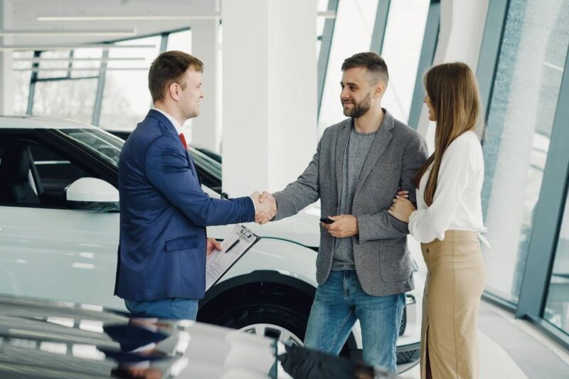 car dealership transaction with happy couple