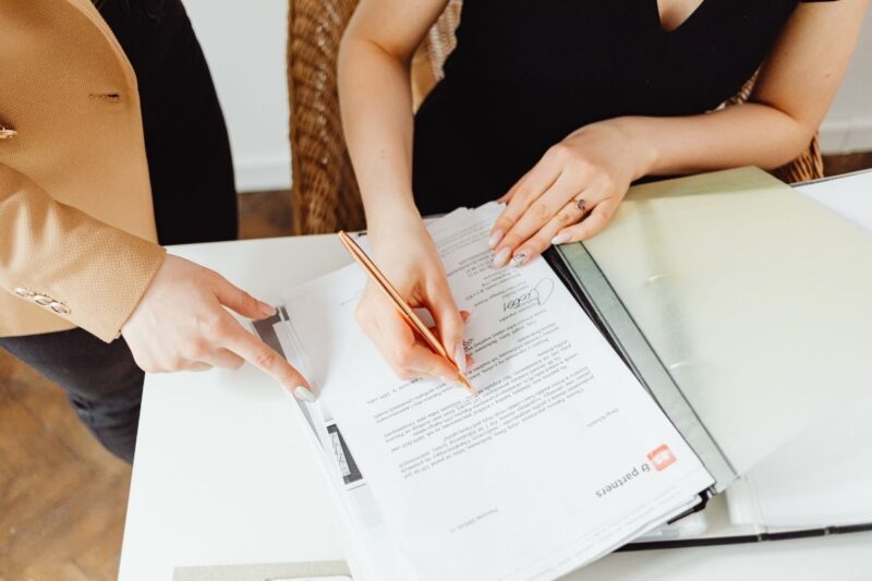 woman signing a legal documents and discussing paperwork